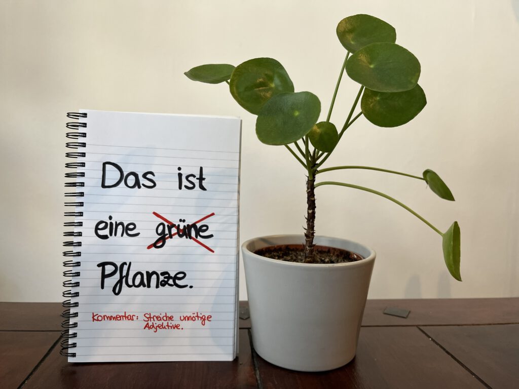 Neben einer Pflanze steht ein Block, auf den eine Lektorats-Anweisung geschrieben ist.